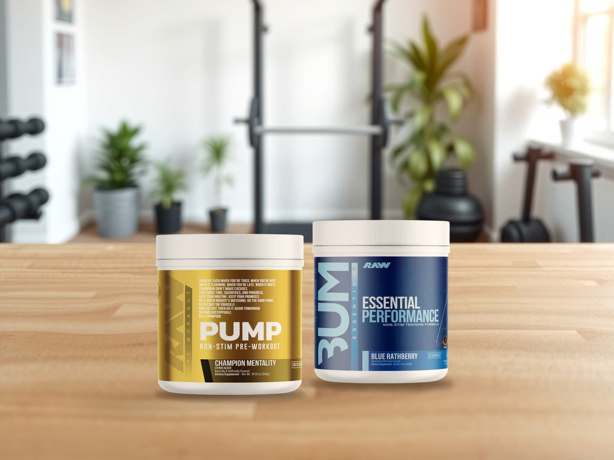 RAW Pump Non-Stim Pre-Workout Champion Mentality and RAW Essential Performance Pre-Workout Blue Rathberry tubs on a light oak counter in a bright home gym, products clearly in focus
