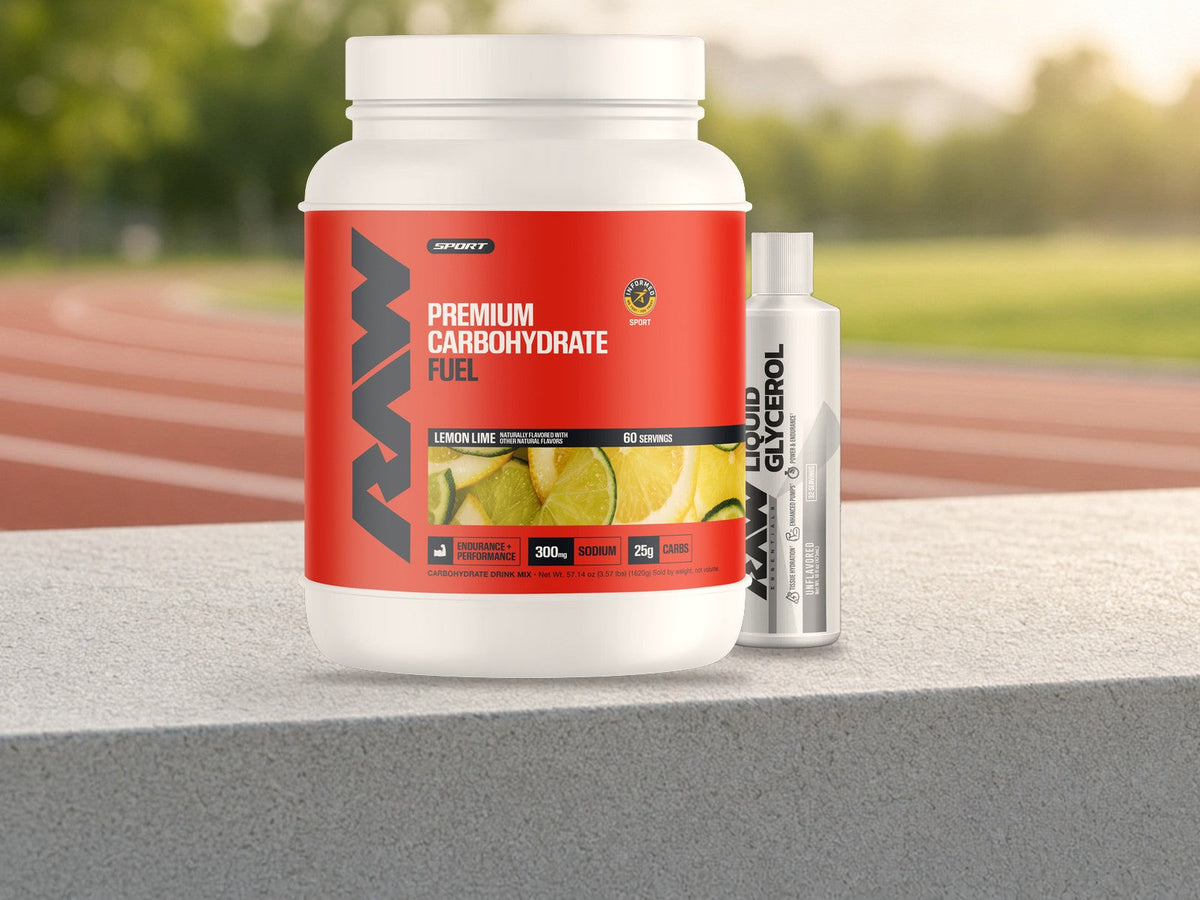 RAW Fuel Carbohydrate Drink Mix Lemon Lime tub beside a RAW Liquid Glycerol bottle on a concrete ledge by an outdoor running track in golden morning light, products clearly in focus