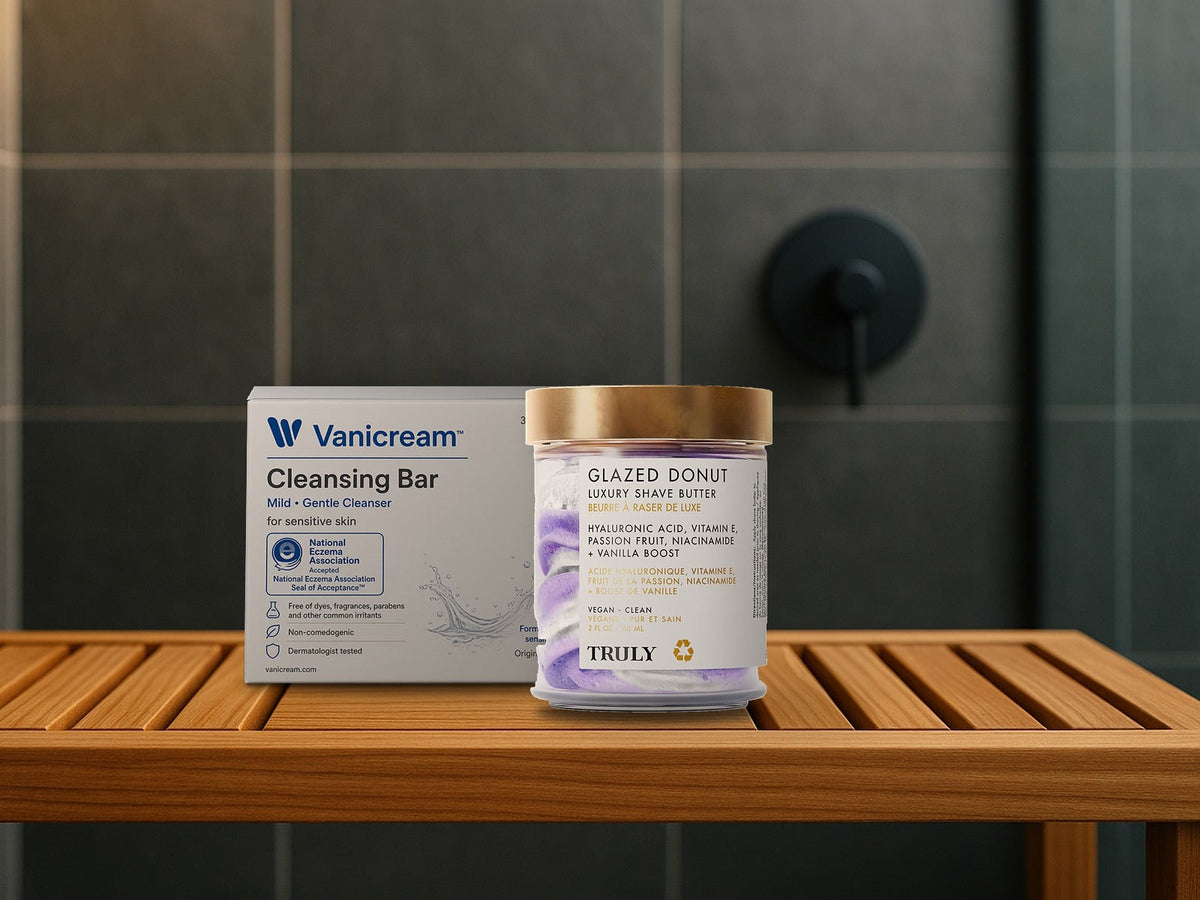 Truly Beauty Glazed Donut Shave Butter jar and Vanicream Cleansing Bar box on a teak shower bench in front of charcoal slate tile, product clearly in focus